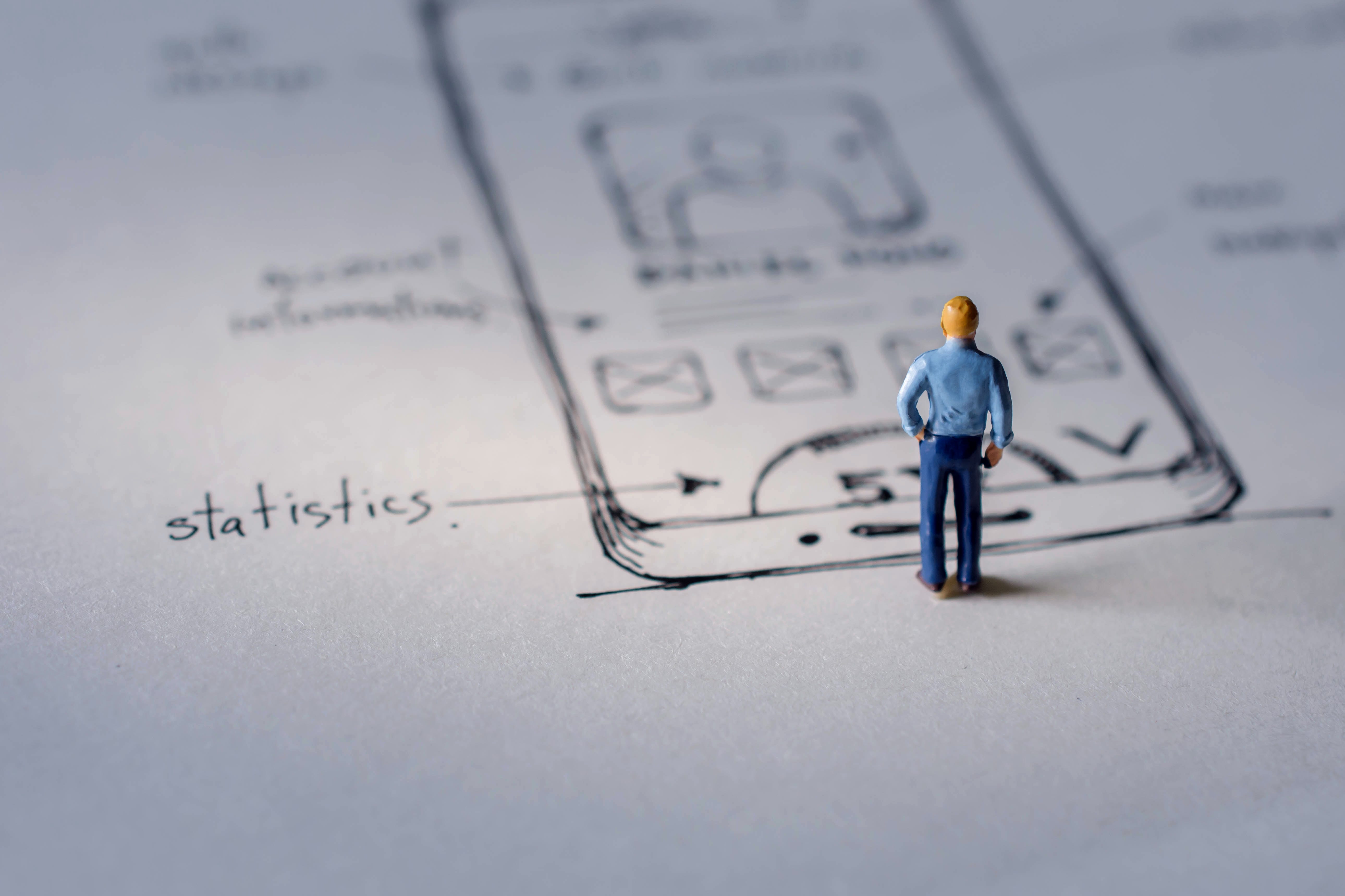 User Experience Concept. present by Miniature Figure of UX UI Designer standing on Paper of Interface Design Sketch